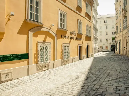 (c) Hotel König von Ungarn The yellow-painted facade of the Hotel König von Ungarn in Vienna, looking down the deserted, cobblestone street (c) Photo: Hotel König von Ungarn
