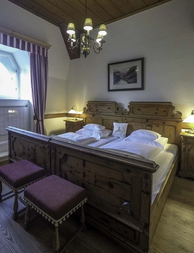 Antique solid wood double bed with wooden floor and ceiling at Landhaus Koller in Gosau, Salzkammergut