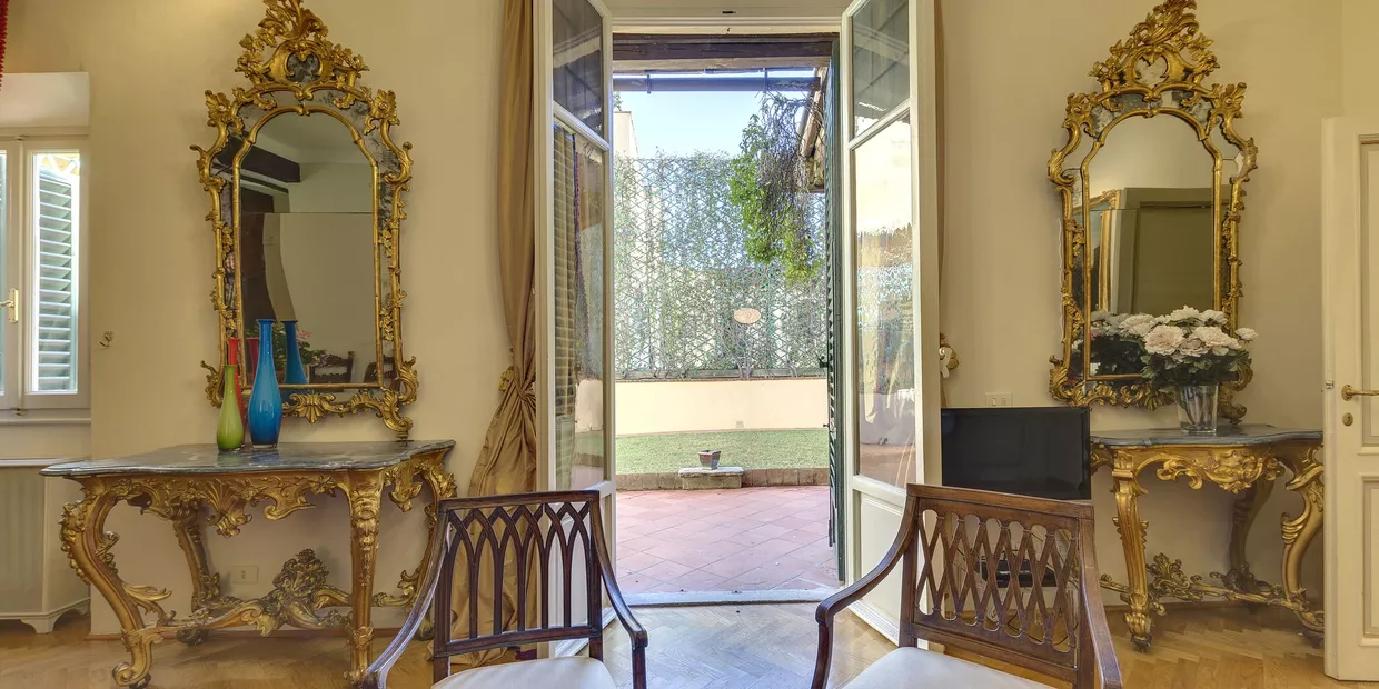 Hell eingerichtes Wohnzimmer mit Blick auf die Terrasse mit Garten des Appartements im Palazzo Larderel in Florenz, Italien