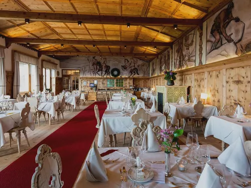 “Riese Grimm” dining hall with wall fresco and festively decked-out tables in the historic restaurant of Hotel Der Zirmerhof in Radein, South Tyrol
