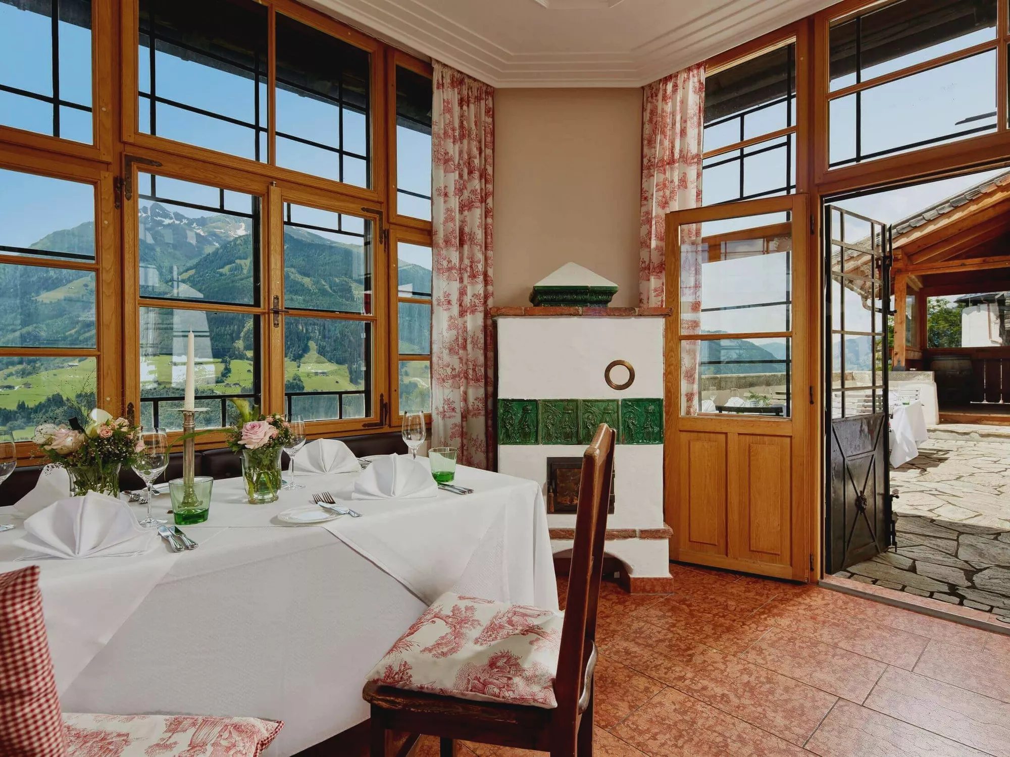 Gedeckte Tische im Restaurant Schloss Mittersill mit Ausblick durch grosse Fenster auf die umliegenden Berge