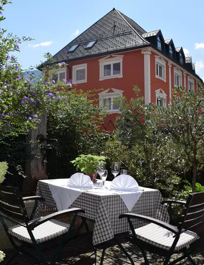 Set tables in the pleasant, shady outdoor dining area of restaurant Gasthof Herrnhaus in Brixlegg, Tyrol