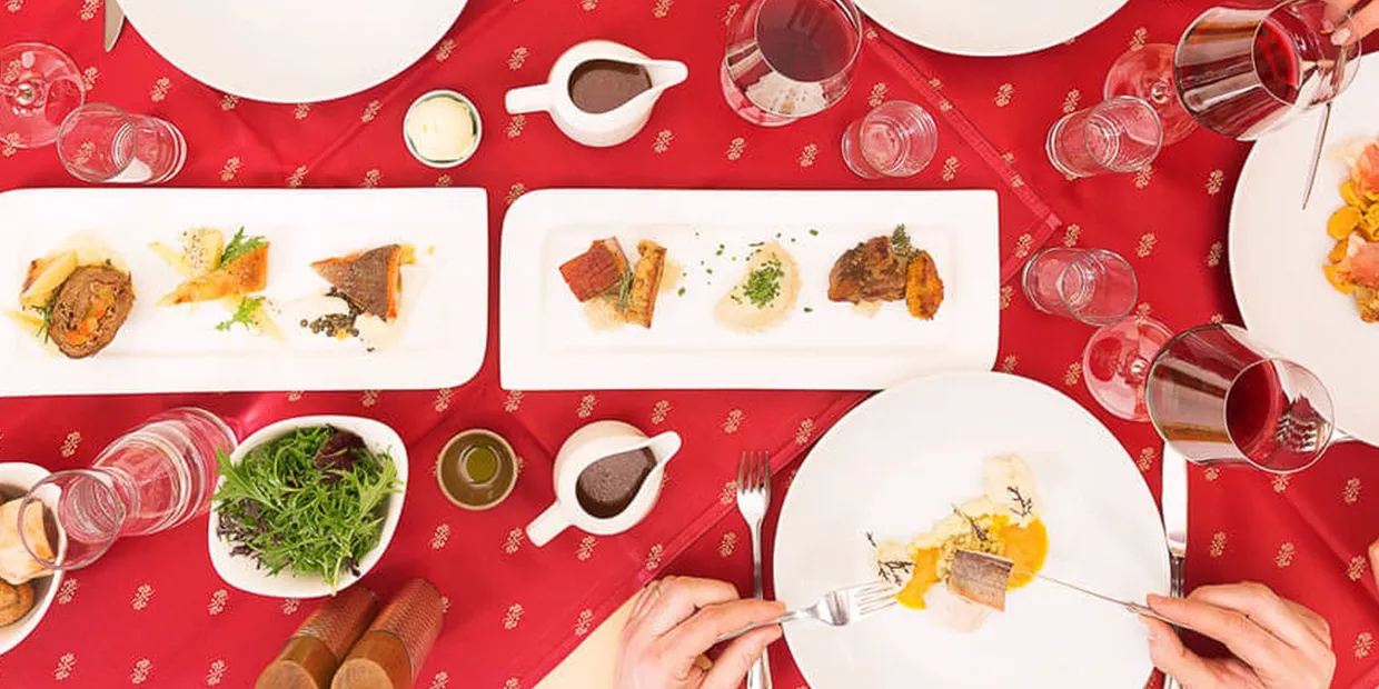 Mittagstisch mit verschiedenen Köstlichkeiten auf weißen Tellern und rotem Tischtuch von oben fotografiert im Hotel Schloss Lerchenhof in Hermagor, Kärnten