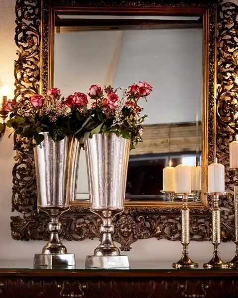 Detailaufnahme eines Spiegels mit schwerem schmiedeeisernen Rahmen, Kerzen und Rosen in silbernen Vasen auf Schloss Mittersill (c) Foto Michael Huber www.huber-fotografie.at