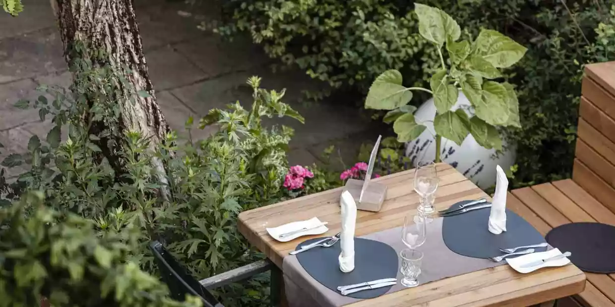 Zweiertisch mit weisser Tischwäche auf der begrünten Terrasse im Restaurant Herrenansitz Strasserwirt in Osttirol (c) Hannes Niederkofler