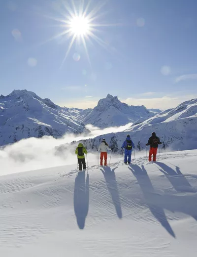 Skifahrer auf der Skipiste mit Blick über das herrlich verschneite Bergpanorama vom Arlberg (c) Foto Tirol Werbung / Josef Mallaun