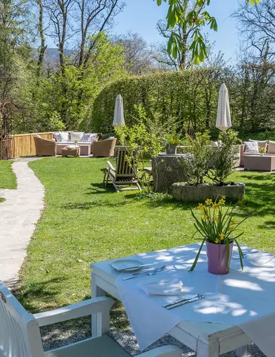 Gedeckte Tische auf der Terrasse mit Blick auf den Garten vom Restaurant Schlosswirt zu Anif bei Salzburg