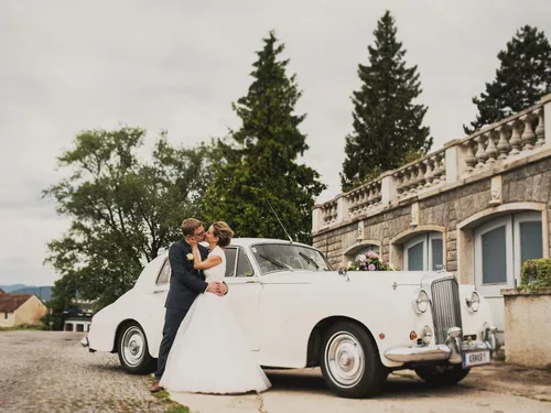Bride and groom kissing in front of a white vintage car at the Sepp Moser winery in Rohrendorf, Lower Austria (c) photo Konstantin Taufner-Mikulitsch