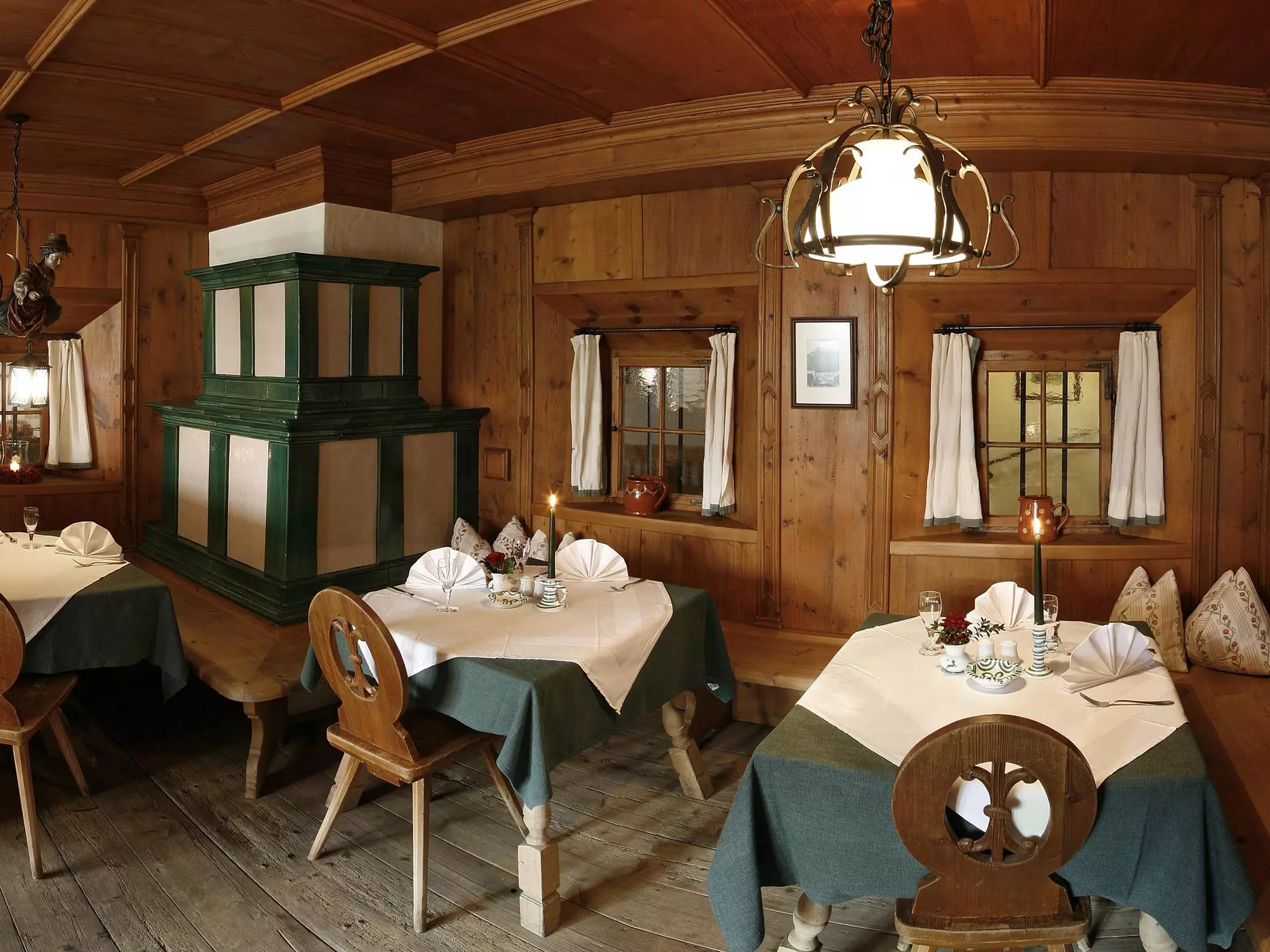 Antique, wood-paneled dining room with set tables at restaurant Gasthof Herrnhaus in Brixlegg in Tyrol