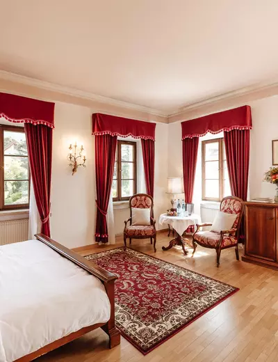 Double room with red curtains at Hotel Castel Rundegg in Merano, South Tyrol