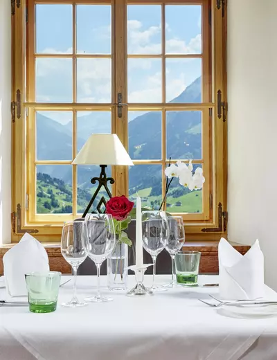 Beautifully set table by the window of the Fireplace Room with view of the valley and mountains at historic Restaurant Schloss Mittersill