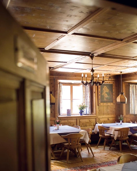 Blick durch halb geöffnete Türe in eine alte Stube mit schön gedeckten Tischen im Hotel Landgasthof Linde in Stumm im Zillertal (c) Heli Hinkel