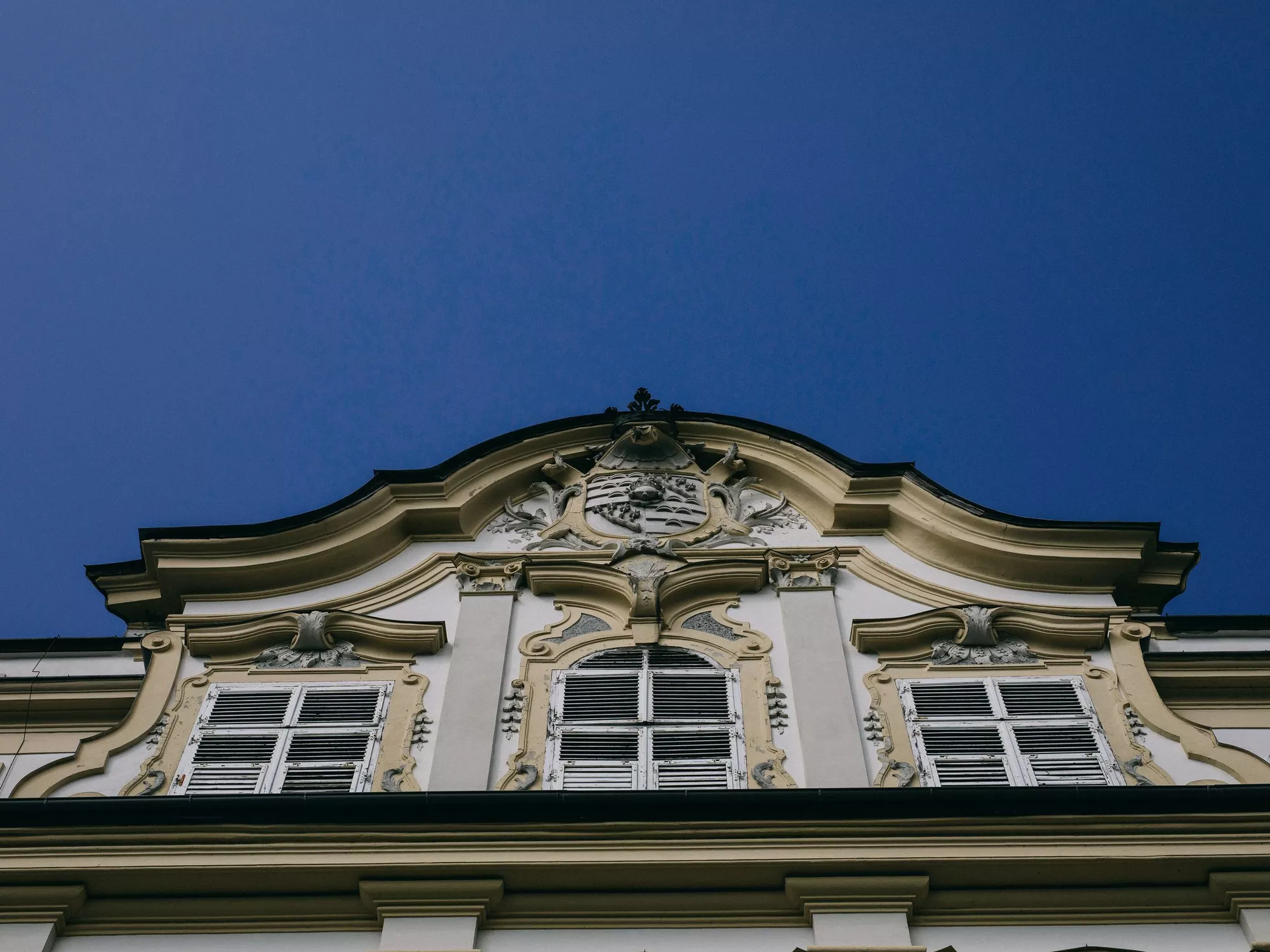 Closeup photo of the gable of Schloss Leopoldskron in Salzburg, photographed from below against the sky (c) Schlosshotels & Herrenhäuser