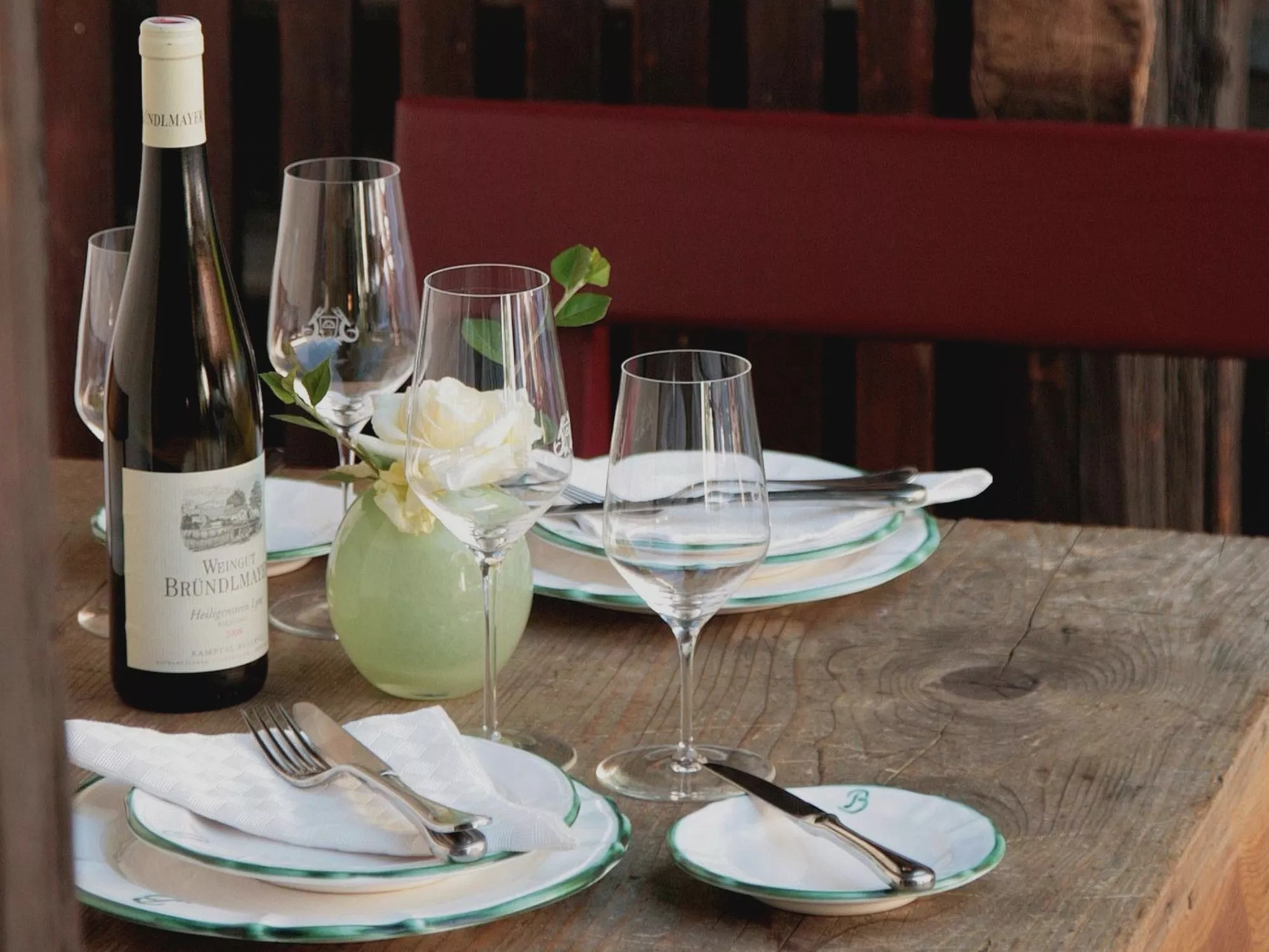 Holztisch mit Gedecken und einer Flasche Wein im Restaurant Heurigenhof Bründlmayer in Langenlois in Niederösterreich