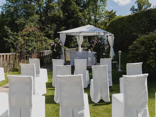 Festliche Stühle mit weißen Houssen für die bevorstehende Trauung im Garten vom Schlosswirt zu Anif südlich von Salzburg