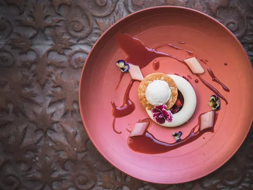 Dessert creation with flower petals on an Indian-red plate at Schloss Hotel Korb in Eppan, South Tyrol (c) photo Koni Studios