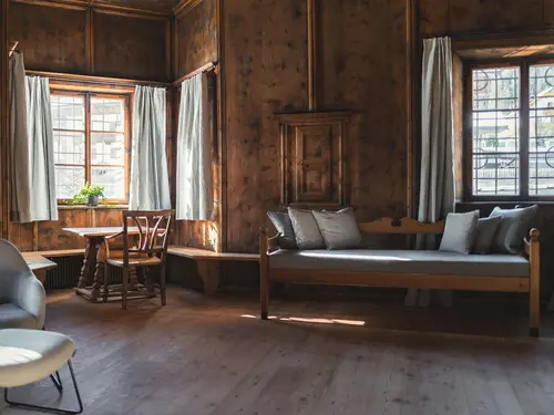 Zimmer im Ansitz Heufler, Südtirol (c) Koni Studios Holzvertäfeltes Zimmer im Ansitz Heufler mit eleganter Sitzbank zwischen zwei Fenstern (c) Foto Koni Studios