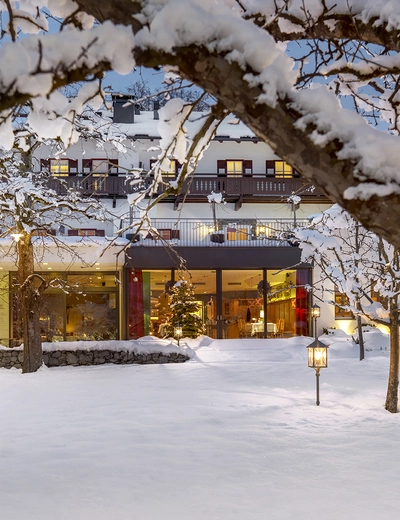 Tief verschneiter Garten in Abendstimmung mit erleuchtetem Hotel Landgasthof Linde in Stumm im Zillertal im Hintergrund (c) Heli Hinkel